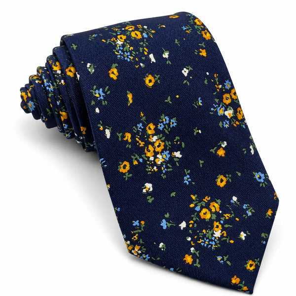 Rolled men's navy blue necktie featuring an all-over yellow and blue ditsy floral print on a white background