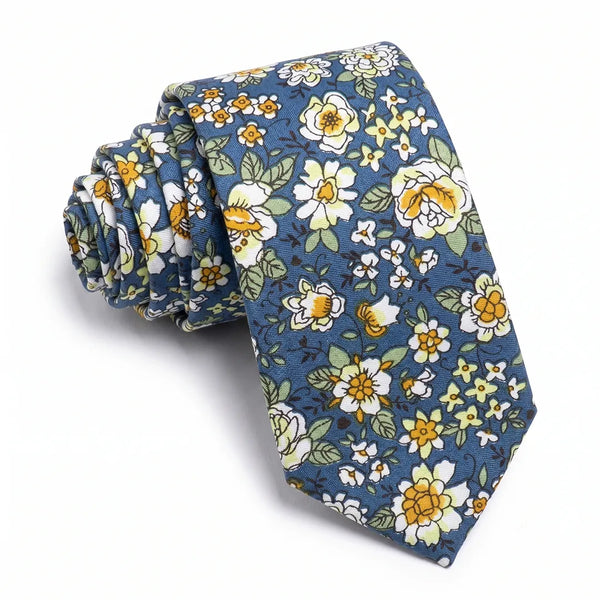 Close-up of a rolled dusty blue cotton necktie featuring a ditsy floral pattern in white and yellow with green foliage.