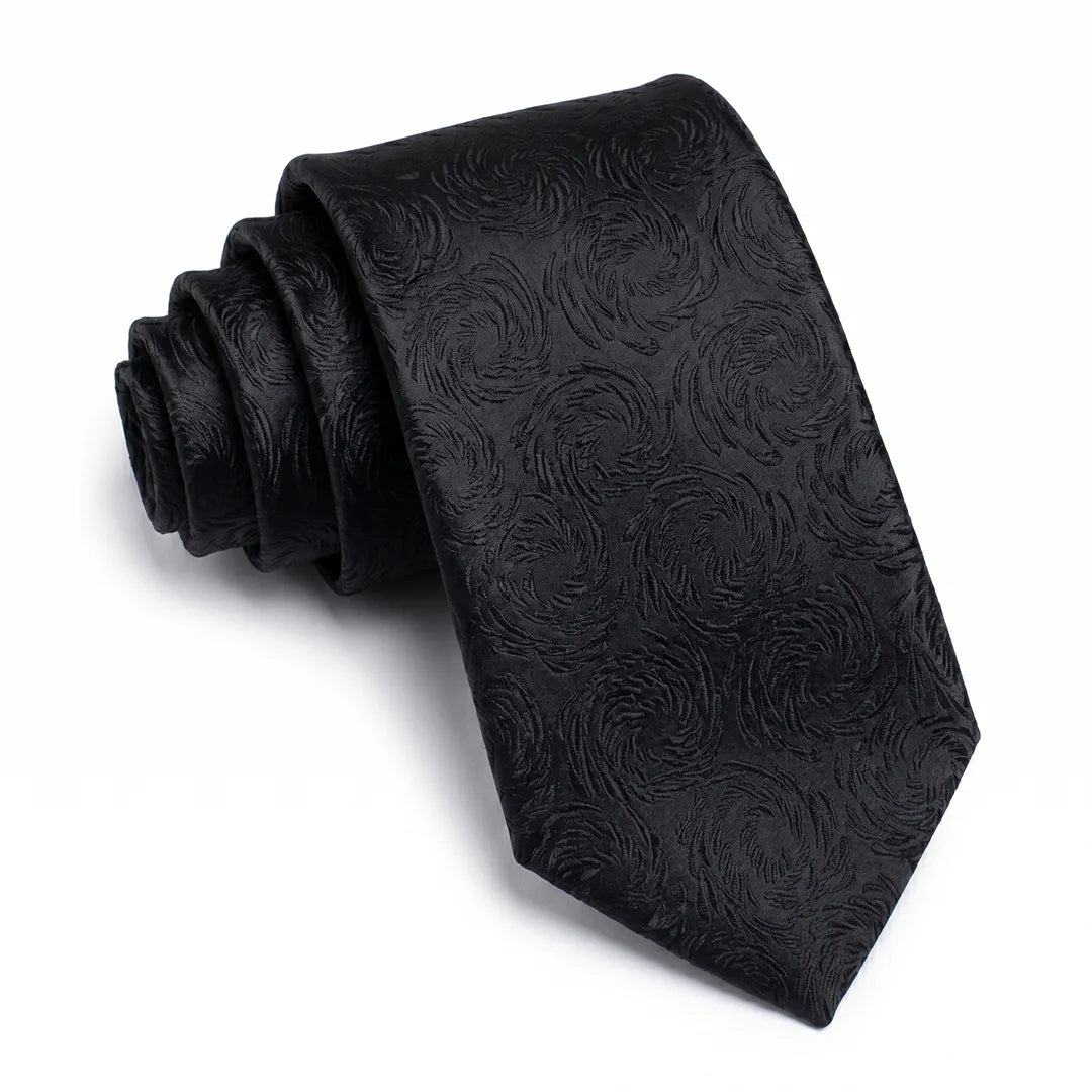 Close-up of a black skinny tie featuring a floral jacquard pattern on a smooth polyester fabric.