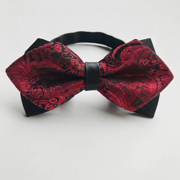 Close-up of a deep red and black paisley jacquard diamond bow tie featuring sharp pointed edges and a solid black center knot on a smooth polyester fabric.
