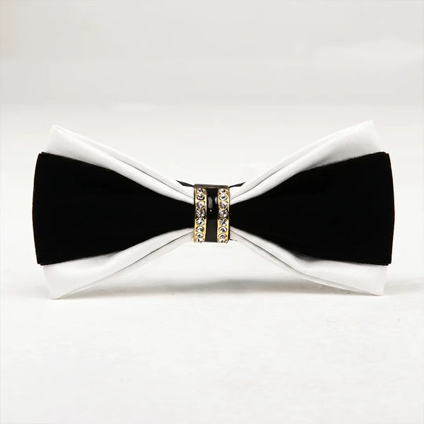 Close-up of a luxurious two-tone white leather and black bow tie featuring a gold metallic ring centerpiece encrusted with clear crystals and black enamel.