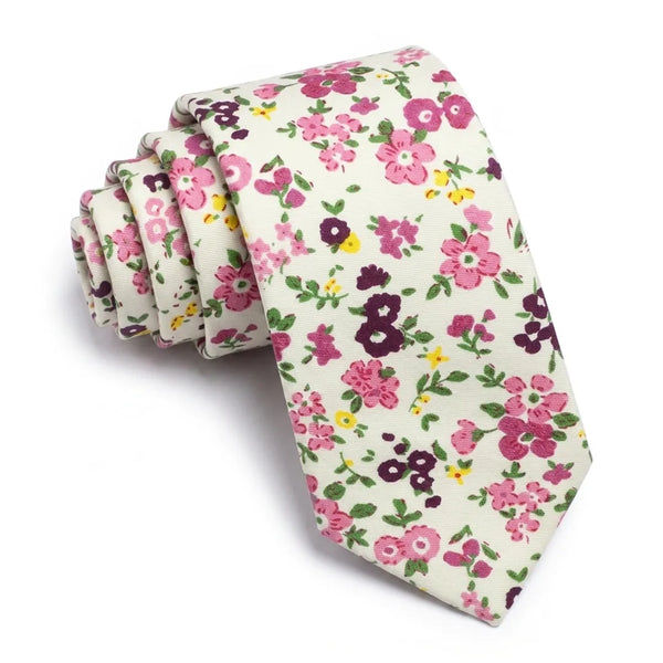Close-up of a rolled white cotton necktie featuring a ditsy floral pattern in pink, plum, and yellow.