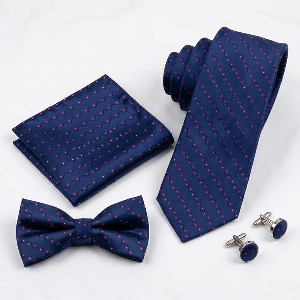 A men's formal accessory set including a navy blue necktie, matching bow tie, pocket square, and silver cufflinks with dark blue round studs, all featuring a small pink dotted pattern on a white background.