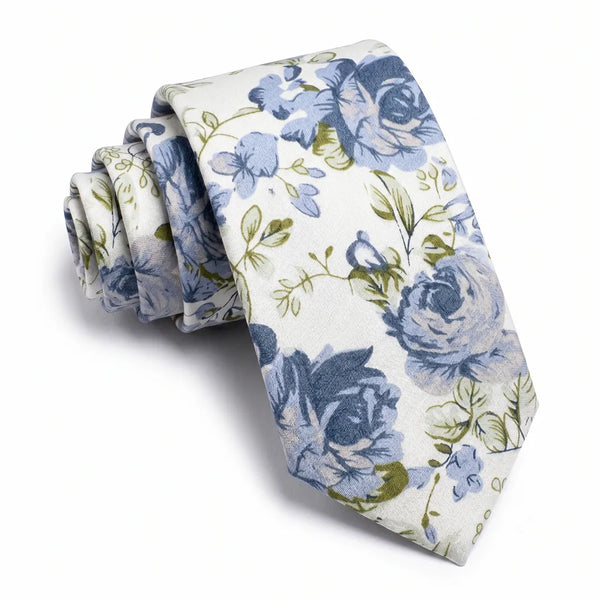 Close-up of a rolled white cotton necktie featuring a painterly floral pattern in shades of blue with olive-green foliage.