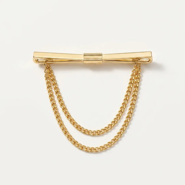 Close-up of a polished gold-tone flat bar collar pin with a smooth center clasp and two tiered, draped curb chains.