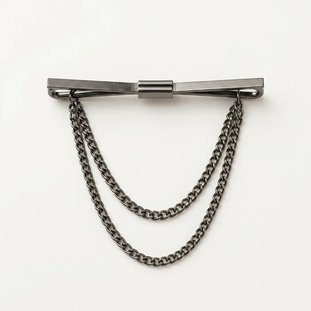 Close-up of a polished dark gunmetal flat bar collar pin with a smooth satin-brushed finish and two tiered, draped curb chains.