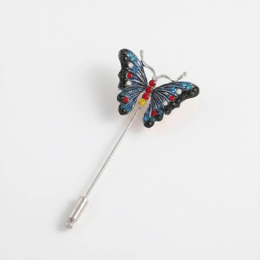 Close-up of a silver-tone butterfly lapel pin featuring deep blue and black enamel wings with red, clear, light blue, and yellow crystal accents on a silver-tone stem.

