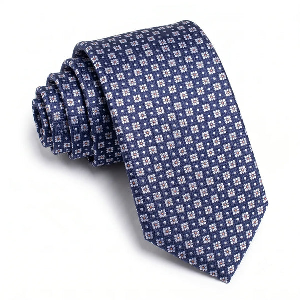 Close-up of a navy blue skinny patterned tie featuring white micro-floral motifs with orange centers on a smooth polyester fabric.