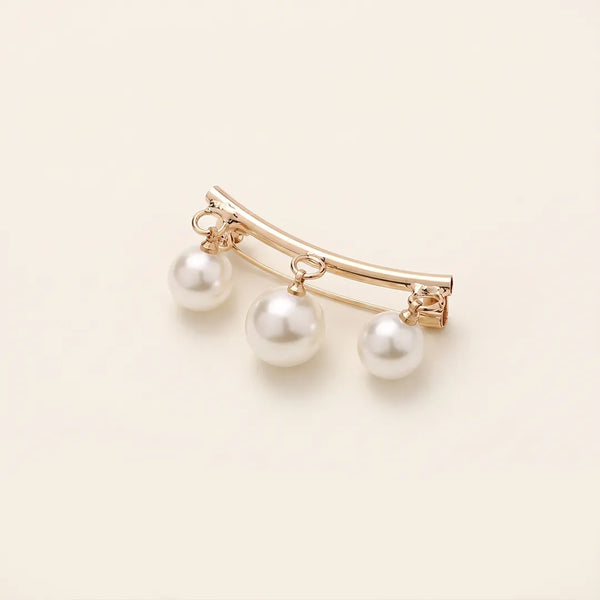Close-up of a polished gold-tone curved bar collar pin featuring three dangling white faux-pearls.