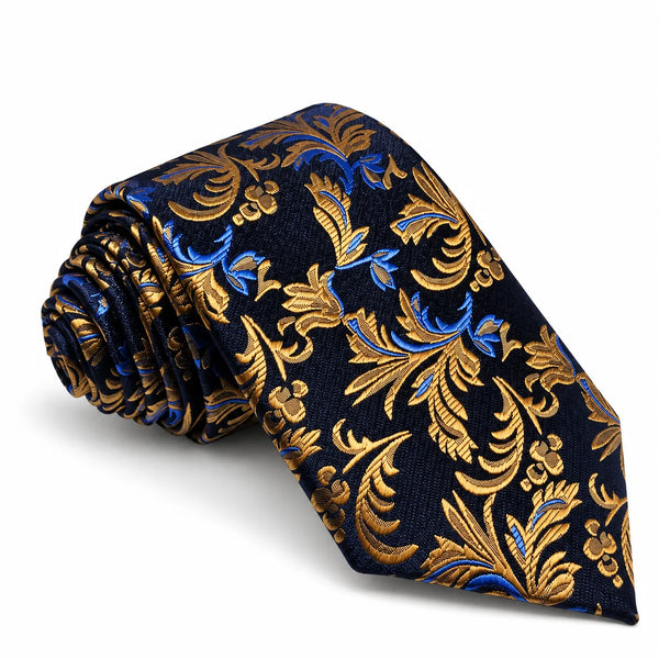 A rolled necktie with a dark navy blue base and an ornate baroque-style pattern in metallic gold and bright blue, displayed on a clean white background.