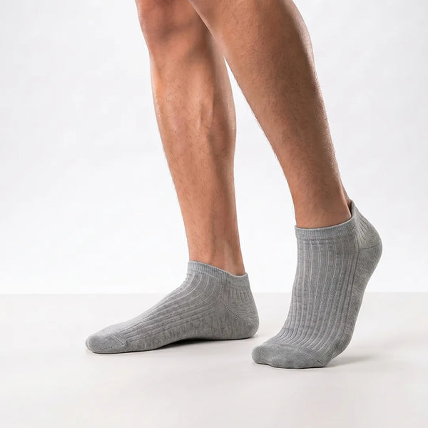 Close-up of a man's feet wearing grey ribbed low-cut ankle socks.