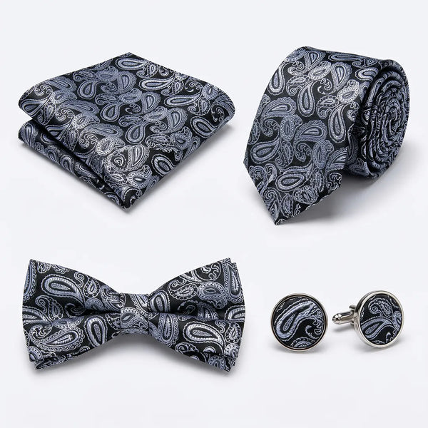 Flat lay of a Sailor Australia black and silver paisley 4-piece tie set including a tie, pocket square, bow tie, and cufflinks.