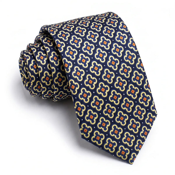 Close-up of a navy quatrefoil tie featuring gold and cream outlines, rust-orange centers, and white dots on a smooth polyester fabric.