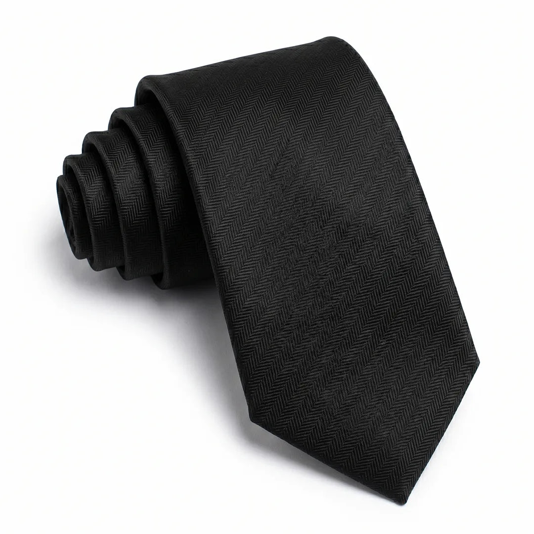 Close-up of a black skinny tie featuring a textured herringbone chevron weave on a smooth polyester fabric.