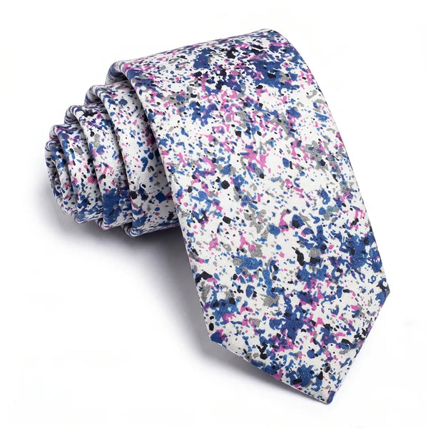 Close-up of a rolled white cotton necktie featuring a colorful paint-splatter pattern in blue, pink, black, and grey.