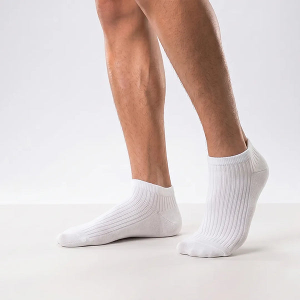 Close-up of a man's feet wearing white ribbed low-cut ankle socks.