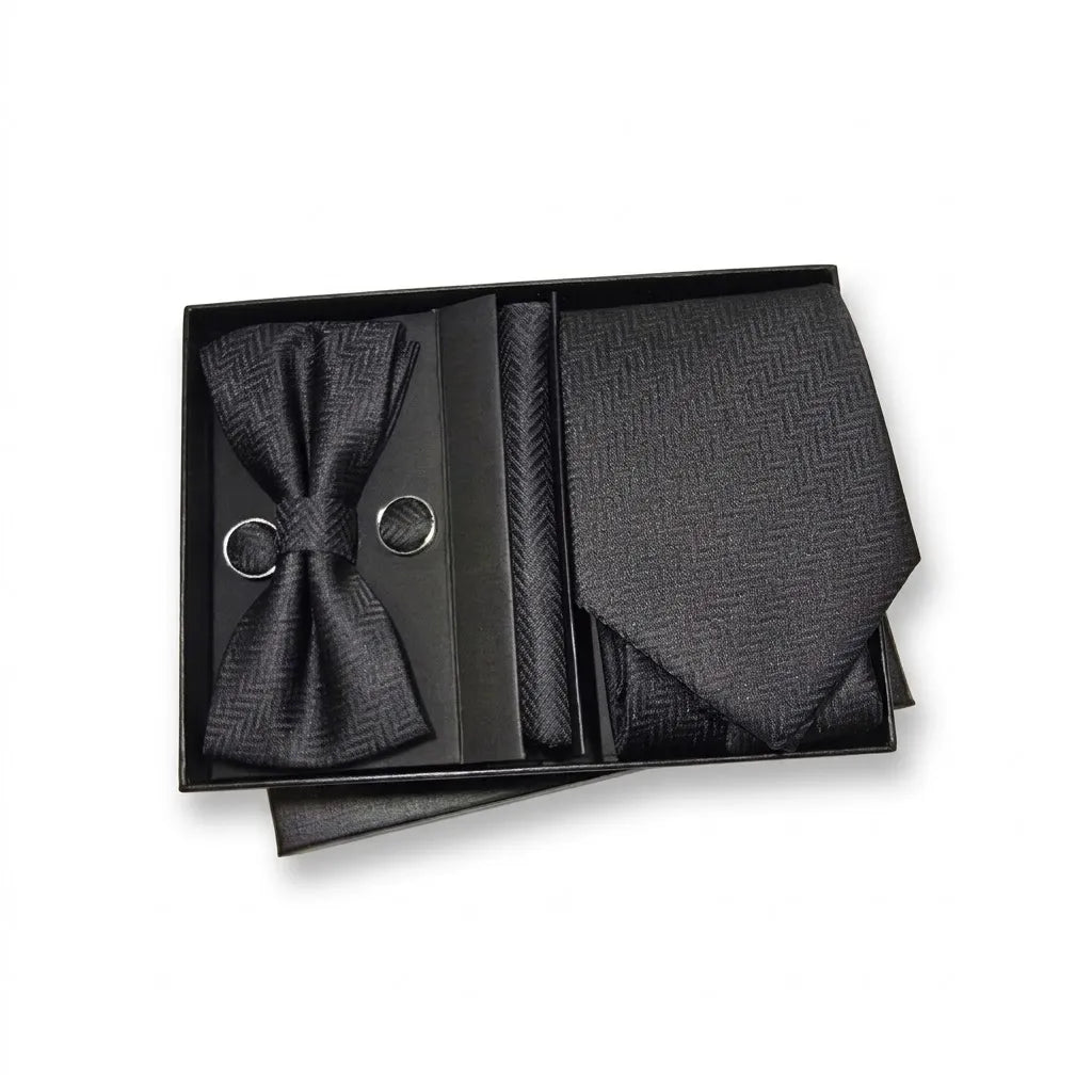 A men's formal accessory set in a black presentation box, featuring a pre-tied bow tie, a necktie, a pocket square, and two silver ring accents, all with a subtle herringbone pattern.