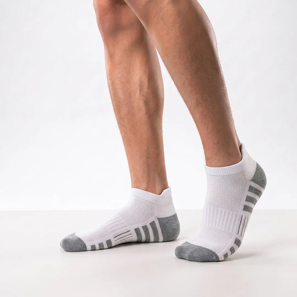 Close-up of a man's feet wearing white sport ankle socks with grey heel and toe caps and grey side stripes.