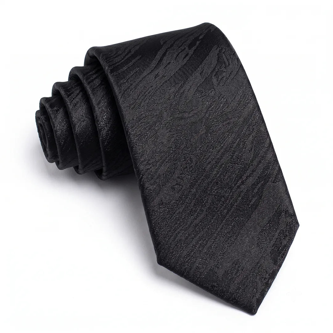 Close-up of a black skinny tie featuring a textured tone-on-tone floral pattern on a smooth polyester fabric.