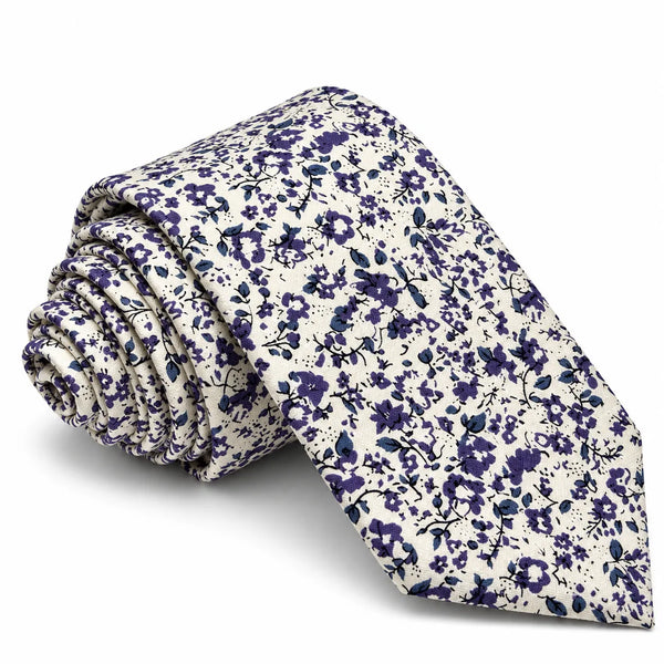 Rolled off-white cotton slim necktie featuring an all-over ditsy indigo blue floral blossom print on a white background