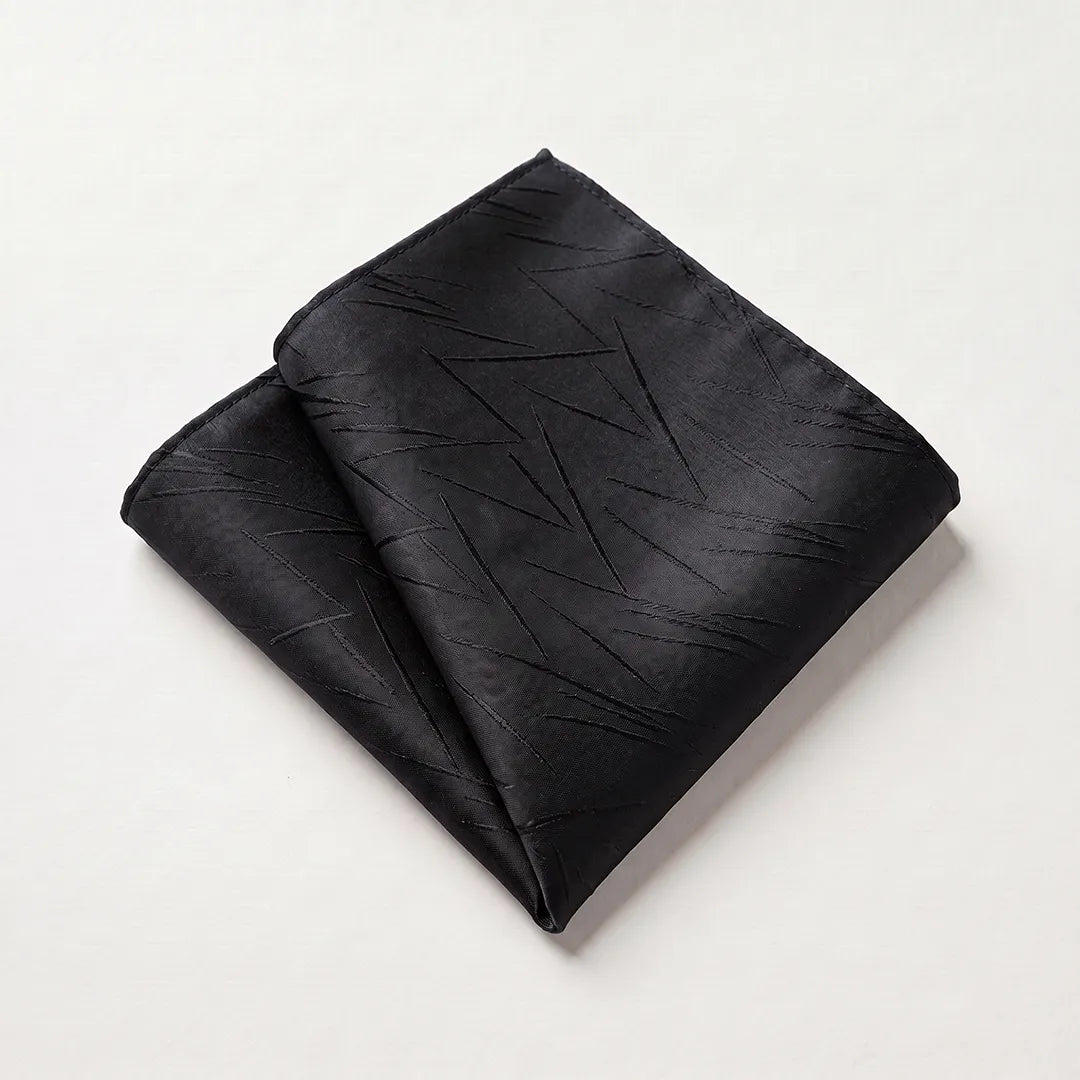 Close-up of a folded black pocket square featuring a modern abstract woven line pattern on a premium polyester fabric.