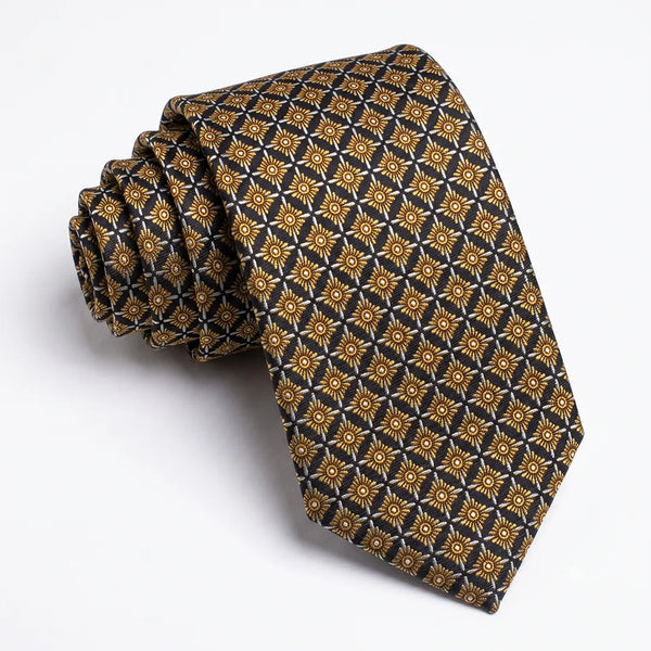 Close-up of a black and gold geometric starburst necktie featuring repeating yellow sunburst motifs and white grid lines on a smooth polyester fabric.
