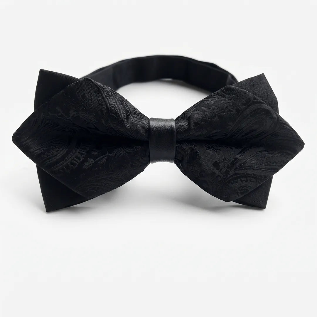 Close-up of a black jacquard paisley diamond bow tie featuring sharp pointed edges and a solid black center knot on a smooth polyester fabric.