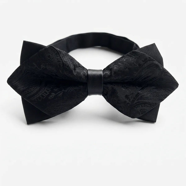 Close-up of a black jacquard paisley diamond bow tie featuring sharp pointed edges and a solid black center knot on a smooth polyester fabric.