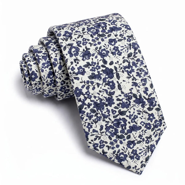 Close-up of a rolled white cotton necktie featuring a high-contrast navy blue ditsy floral pattern.