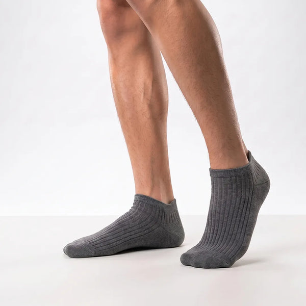 Close-up of a man's feet wearing dark grey ribbed low-cut ankle socks.