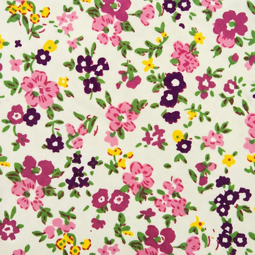Macro close-up showing the matte cotton weave texture and printed magenta, plum, and yellow wildflower blossoms of the necktie