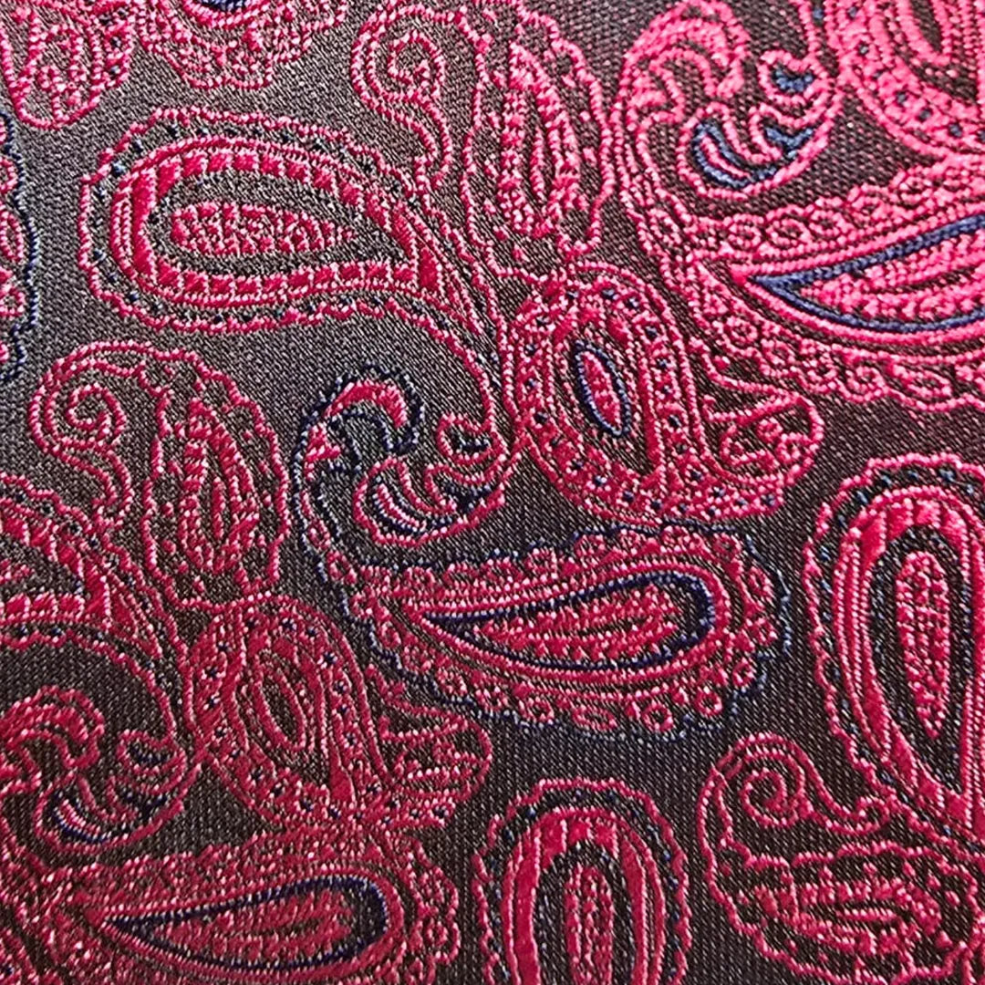 A close-up of a woven paisley fabric with bright pink and magenta motifs over a dark brown background.