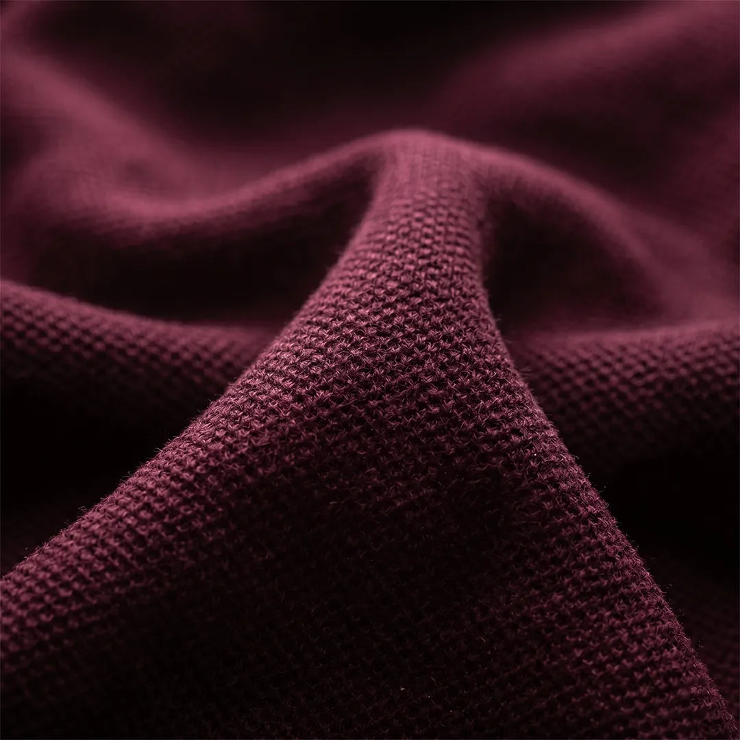 Macro close-up of the syrah red pique knit fabric texture, showcasing the breathable 60% cotton and 40% polyester blend.